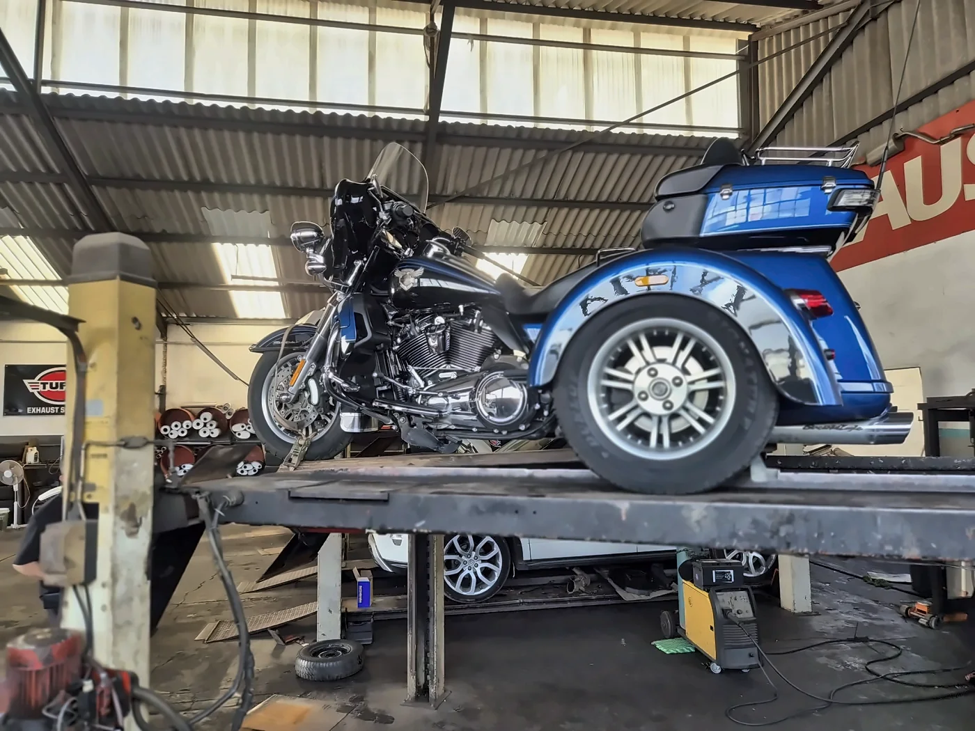 A trike on the lift, the silencer rack behind it